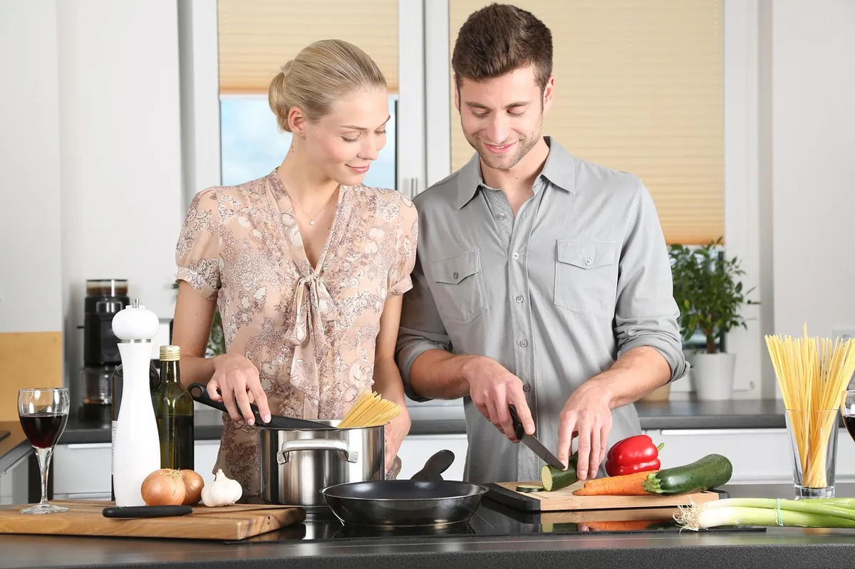 A couple cooking together in a bright kitchen.