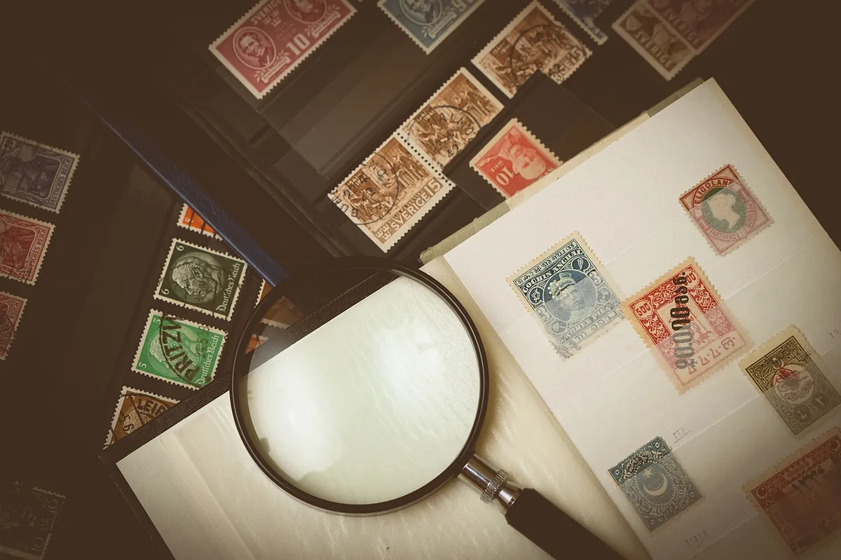 Stamps in an album with a magnifying glass on top.
