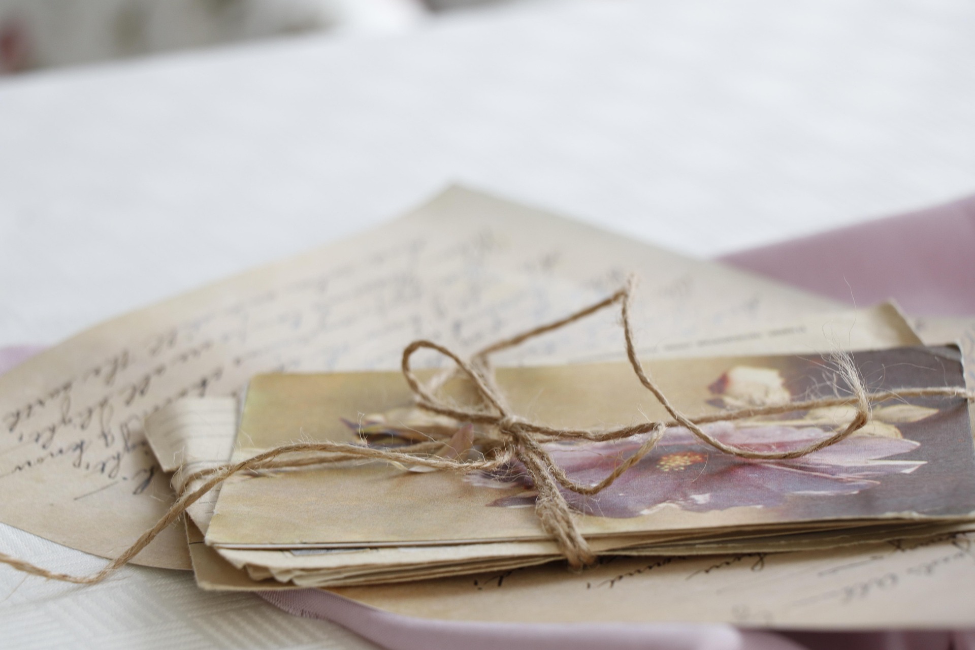 A bundle of old handwritten letters and postcards tied together with twine